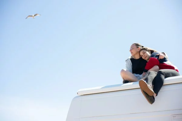 Two women laying on the roof of a campervan